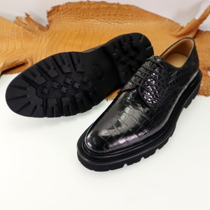 May include: Black leather dress shoes with a crocodile pattern and a thick rubber sole.
