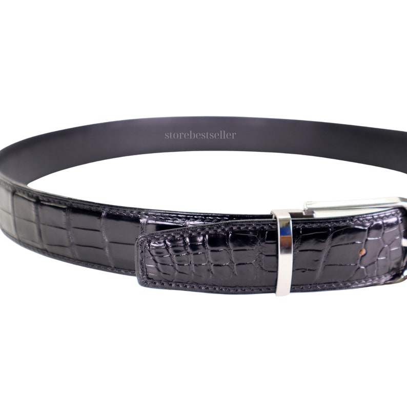 May include: Black alligator leather belt with a silver buckle. The belt is made of genuine alligator leather and has a classic design.