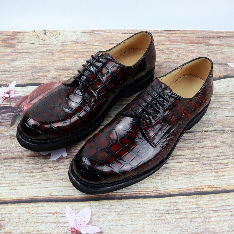 Peut inclure: Une paire de chaussures en cuir marron &agrave; lacets avec un motif crocodile. Les chaussures ont une semelle en caoutchouc noir.