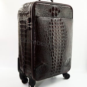 May include: A brown leather suitcase with a crocodile pattern. The suitcase has a retractable handle and four wheels.
