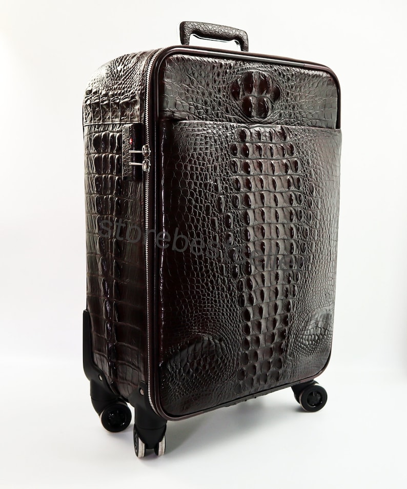 May include: A brown leather suitcase with a crocodile pattern. The suitcase has a retractable handle and four wheels.