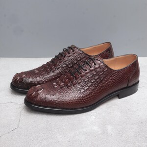 May include: A pair of brown leather lace-up shoes with a crocodile-embossed pattern.