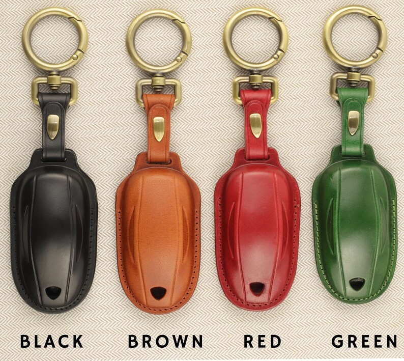 May include: Four leather keychains in black, brown, red, and green. Each keychain has a gold metal ring and a leather loop.
