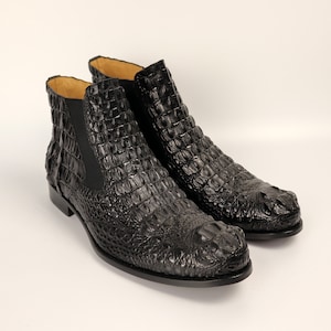 May include: A pair of black leather ankle boots with a crocodile pattern. The boots have a pointed toe and a low heel.