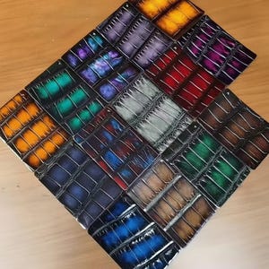 May include: A collection of leather wallets in various colors, arranged in a diamond shape. The wallets feature a textured, crocodile-like pattern and a range of hues, including orange, purple, blue, and green. The wallets are displayed on a light brown wooden surface.