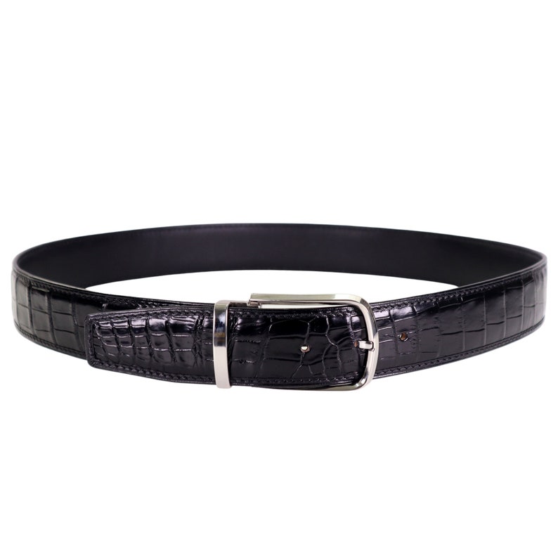Black leather belt with silver-tone buckle, featuring glossy crocodile-style texture, rounded edges, and stitched detailing, displayed in a circular form on a white background.
