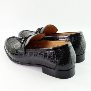 May include: Black leather loafers with a crocodile pattern and tassel detail.