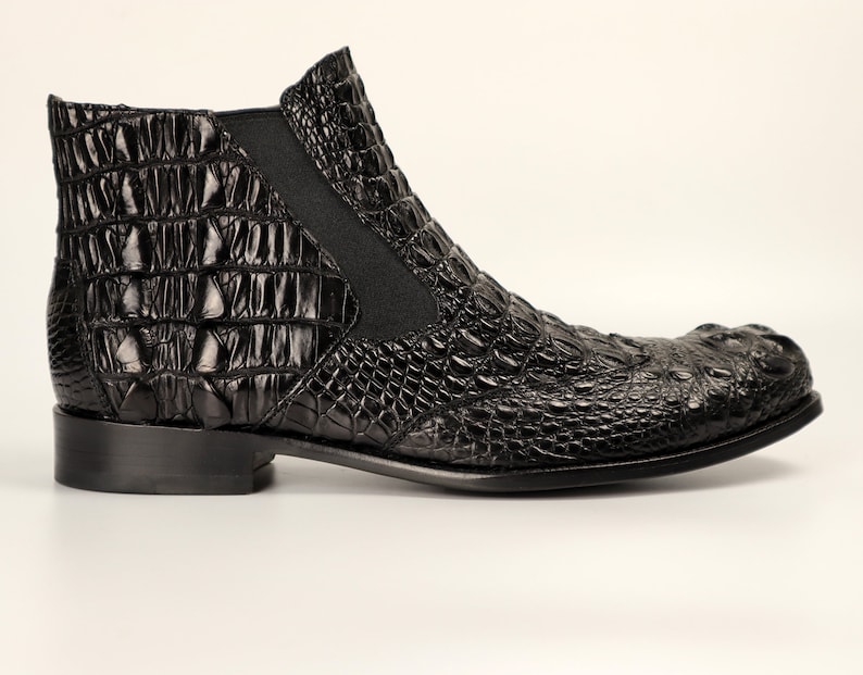 May include: Black leather ankle boots with a crocodile pattern.