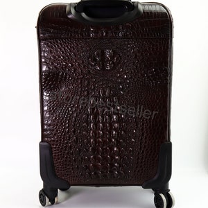 May include: A brown leather suitcase with a crocodile pattern. The suitcase has a retractable handle and four wheels.