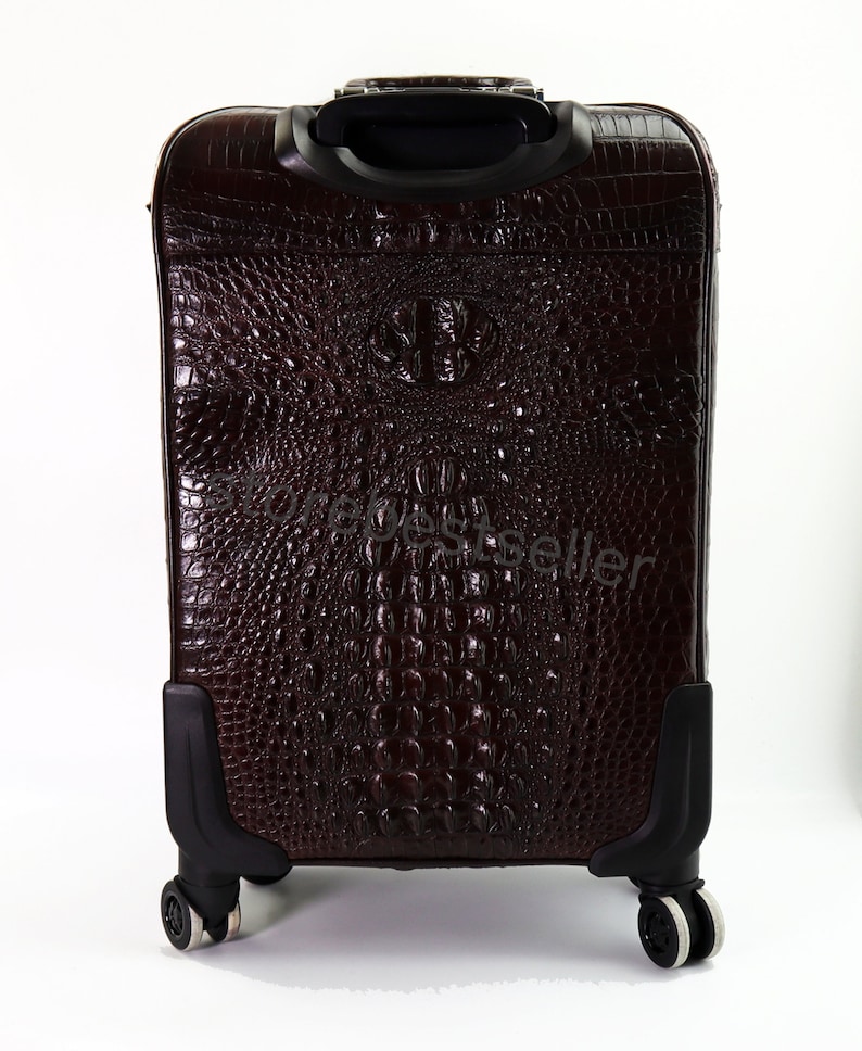 May include: A brown leather suitcase with a crocodile pattern. The suitcase has a retractable handle and four wheels.