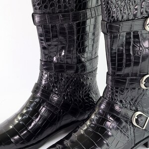 May include: A pair of black leather boots with a crocodile pattern and multiple buckles.