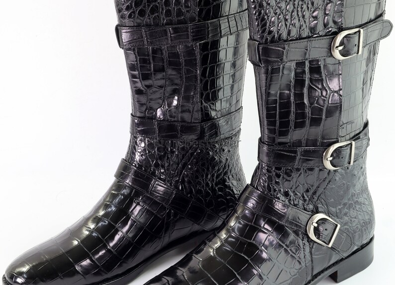May include: A pair of black leather boots with a crocodile pattern and multiple buckles.