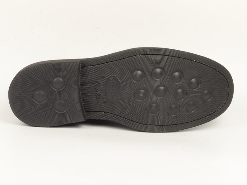 May include: The bottom of a black leather shoe with a textured sole and a small logo that says "Walk On" in white.