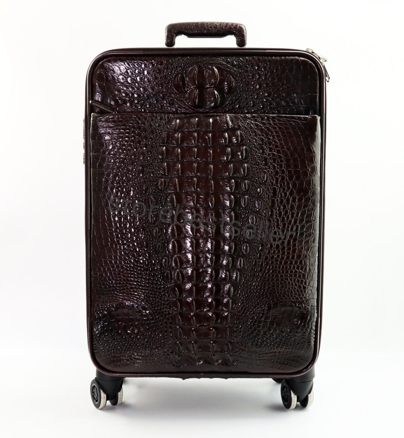 May include: A dark brown crocodile-embossed leather suitcase with a single handle and four wheels.