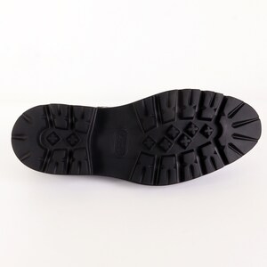 May include: Close-up of the black rubber sole of a shoe with a textured pattern.