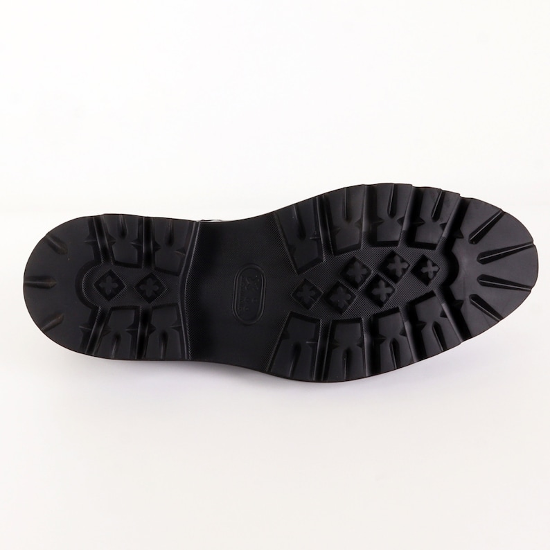 May include: Close-up of the black rubber sole of a shoe with a textured pattern.