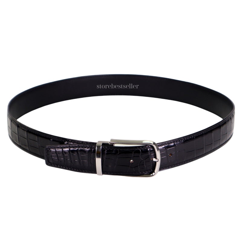 May include: A black leather belt with a crocodile pattern and a silver buckle. The belt is made of genuine leather and is a stylish accessory for any man.