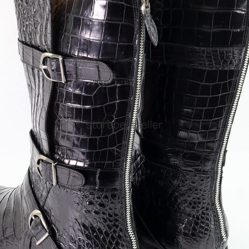 May include: Black leather boots with a crocodile pattern and multiple buckles. The boots have a zipper on the side.