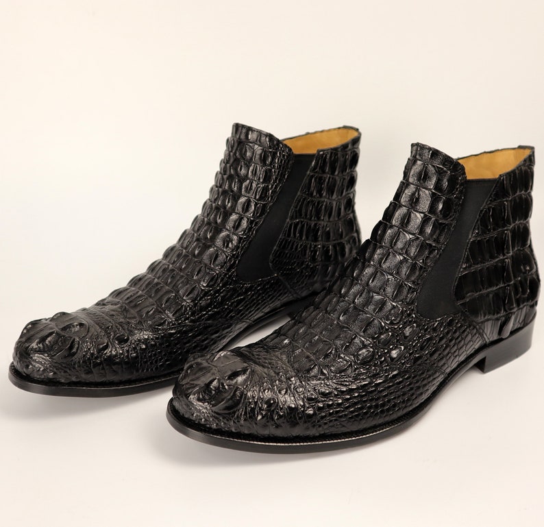 May include: A pair of black leather ankle boots with a crocodile pattern. The boots have a pointed toe and a low heel.