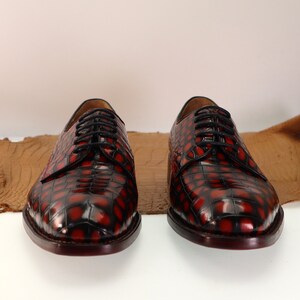 May include: A pair of red and black leather lace-up shoes with a crocodile pattern.