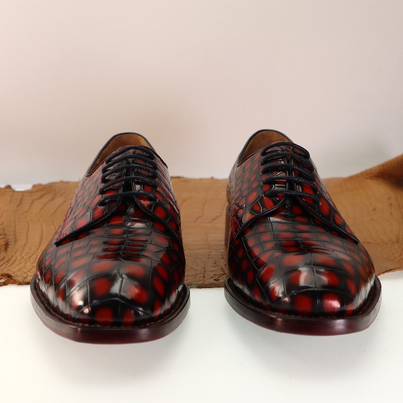 May include: A pair of red and black leather lace-up shoes with a crocodile pattern.