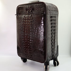 May include: A brown leather suitcase with a crocodile pattern. The suitcase has four wheels and a retractable handle.