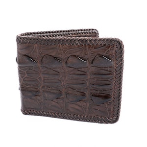 Puede incluir: Una cartera de cuero marrón con un patrón de piel de cocodrilo y un borde trenzado.