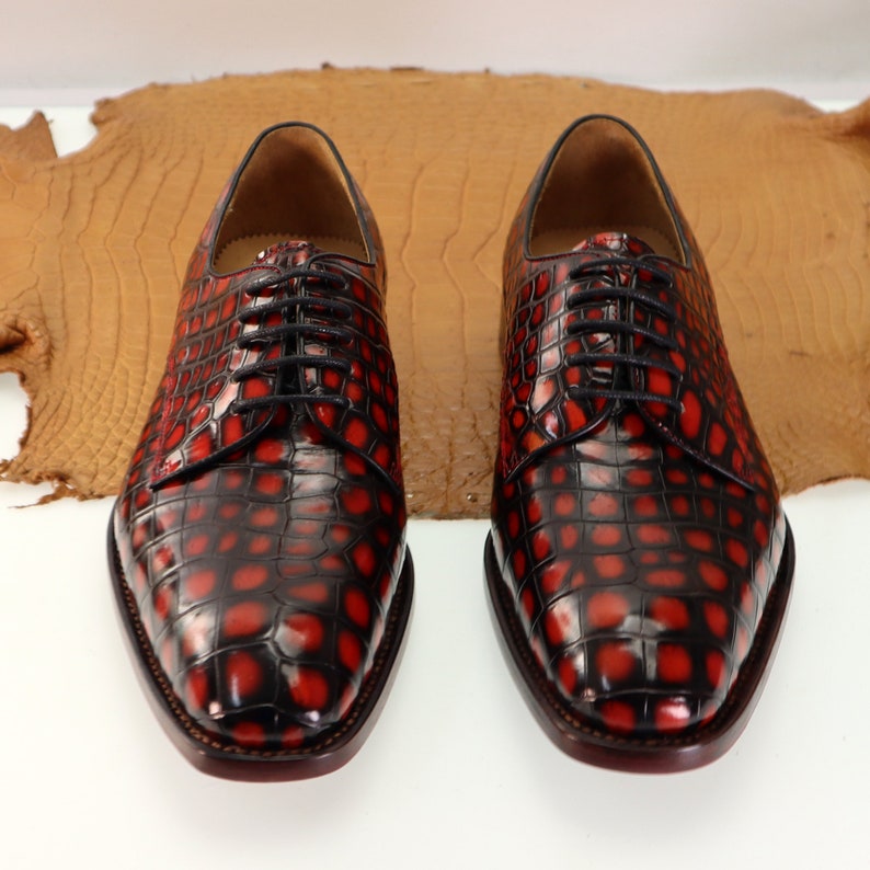 May include: A pair of black leather lace-up shoes with a red crocodile pattern.
