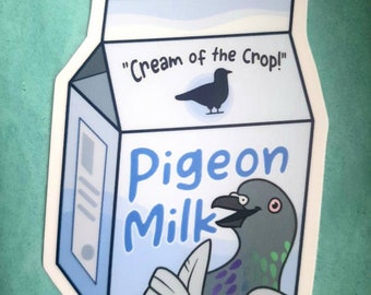 Könnte beinhalten: Ein blauer und weißer Karton mit dem Text "Pigeon Milk" und dem Satz "Cream of the Crop!" Auf dem Karton ist ein Cartoon-Taube mit einem roten Auge abgebildet.
