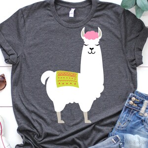 May include: A dark gray t-shirt with a white llama graphic. The llama has a pink headband and a green and red patterned saddle.