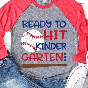 May include: A grey and red baseball-themed t-shirt with the text "Ready to Hit Kinder Garten:" and a baseball graphic.