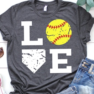 May include: A gray t-shirt with the word "LOVE" printed in white. The "O" is replaced with a yellow softball with red stitching. The "V" is replaced with a white baseball diamond.