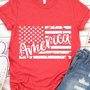 May include: Red t-shirt with a white distressed American flag design and the word "America" written in a white cursive font.