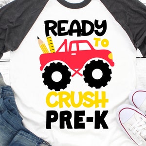 May include: A white t-shirt with a red monster truck graphic and the text "Ready to Crush Pre-K". The monster truck has a yellow ruler and pencil sticking out of the back.