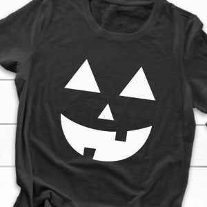 May include: Black t-shirt with a white jack-o'-lantern face graphic.