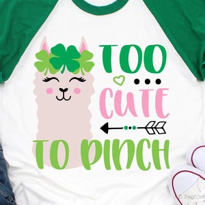May include: A white t-shirt with a green and pink design featuring a llama with a clover crown and the text "Too cute to pinch".
