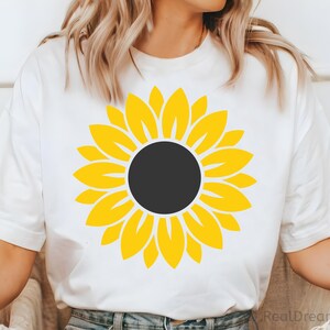 May include: White t-shirt with a yellow sunflower graphic.