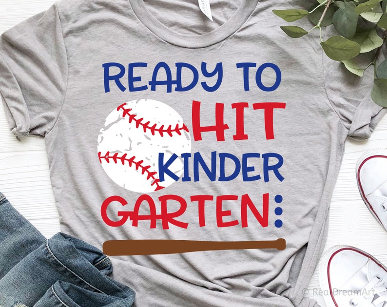 May include: Grey t-shirt with a baseball graphic and the text "Ready to Hit Kinder Garten:" in red and blue lettering. A brown baseball bat is below the text.