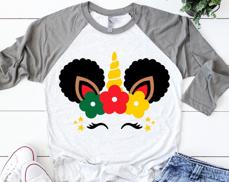 May include: A white and gray raglan t-shirt with a black and brown unicorn design. The unicorn has red, yellow, and green flowers on its head and a gold horn.