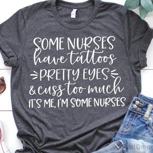 May include: Dark gray t-shirt with white text: "SOME NURSES have tattoos PRETTY EYES & cuss too much IT'S ME, I'M SOME NURSES." Sunglasses and denim jeans are also visible.