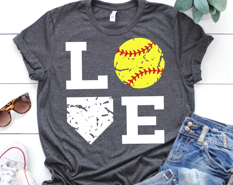 May include: A gray t-shirt with the word "LOVE" printed in white. The "O" is replaced with a yellow softball with red stitching. The "V" is replaced with a white baseball diamond.