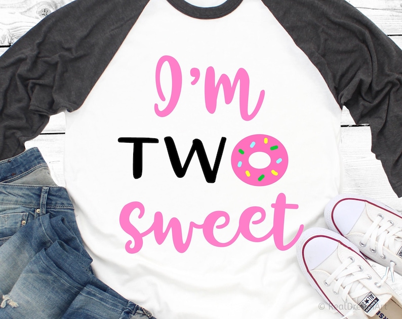 May include: A white and grey baseball tee shirt with pink lettering that says "I'm TWO sweet" and a pink donut with colorful sprinkles.