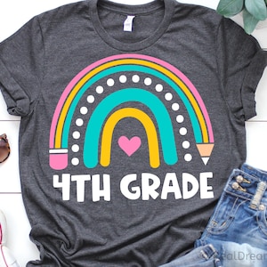 May include: A dark gray t-shirt with a rainbow design and the text "4TH GRADE". The rainbow is made up of pink, yellow, turquoise, and white. There is a small pink heart in the center of the rainbow.