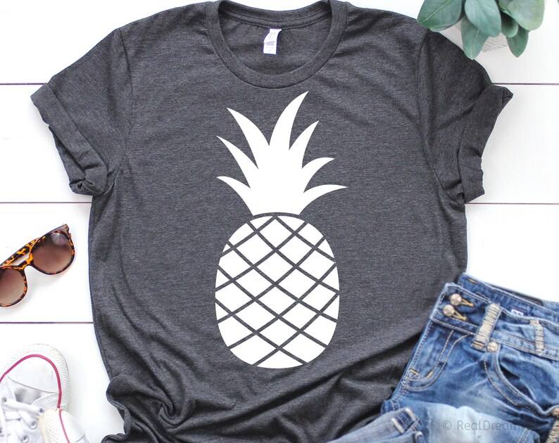 K&ouml;nnte beinhalten: Ein dunkelgraues T-Shirt mit einem wei&szlig;en Ananas-Motiv. Die Ananas ist eine einfache Silhouette mit einer detaillierten Umrandung der Frucht.