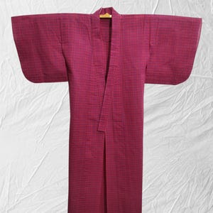 May include: A red and white checkered yukata, a traditional Japanese robe, hanging on a wooden hanger.