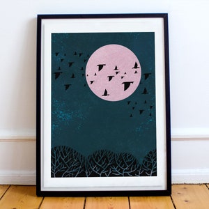 May include: A framed print of a minimalist illustration of a flock of birds flying in front of a large pink moon against a dark blue background. The birds are black silhouettes and the moon is a solid pink circle. The background is a dark blue with a textured look.