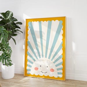 May include: A framed print with a yellow background and a blue and white striped sun with a smiling face. The sun is surrounded by a scalloped border.