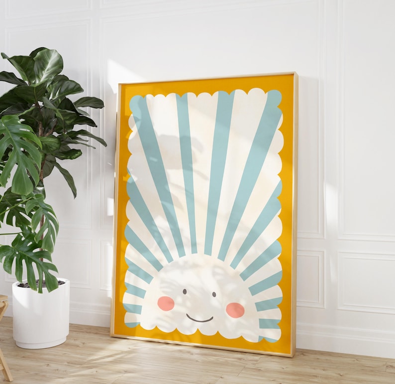 May include: A framed print with a yellow background and a blue and white striped sun with a smiling face. The sun is surrounded by a scalloped border.