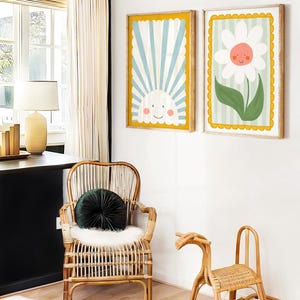 May include: Two framed illustrations with a yellow border. The first illustration shows a blue and white striped background with a smiling sun. The second illustration shows a white daisy with a smiling face on a green and white striped background.