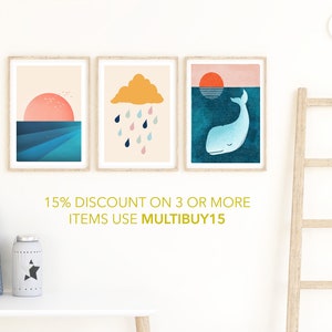 May include: Three framed prints with minimalist illustrations. The first print features a pink sunset over a blue ocean. The second print shows a yellow cloud with raindrops falling from it. The third print depicts a blue whale swimming under a setting sun. The text below the prints reads "15% DISCOUNT ON 3 OR MORE ITEMS USE MULTIBUY15".